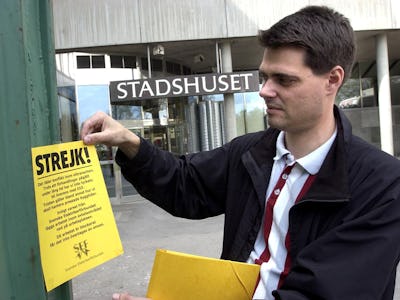 En man med ett gult strejkvarsel utanför en byggnad .