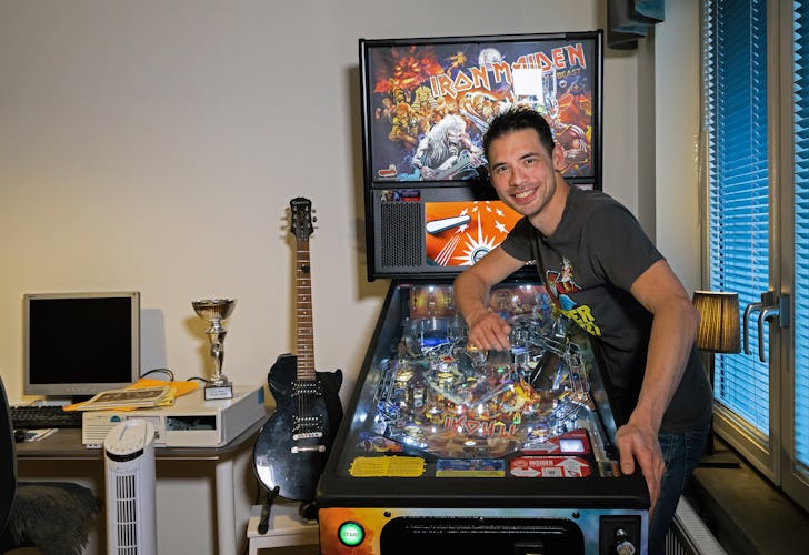 En man står bredvid en flipperspelmaskin med Iron Maiden-tema.