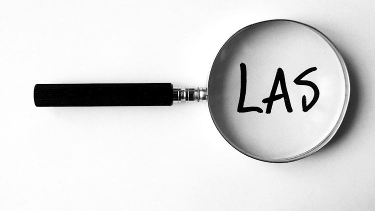 Ett förstoringsglas som ligger över ordet "LAS"