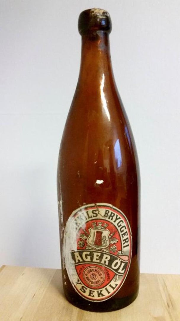 En flaska i brunt glas med en sliten etikett på.