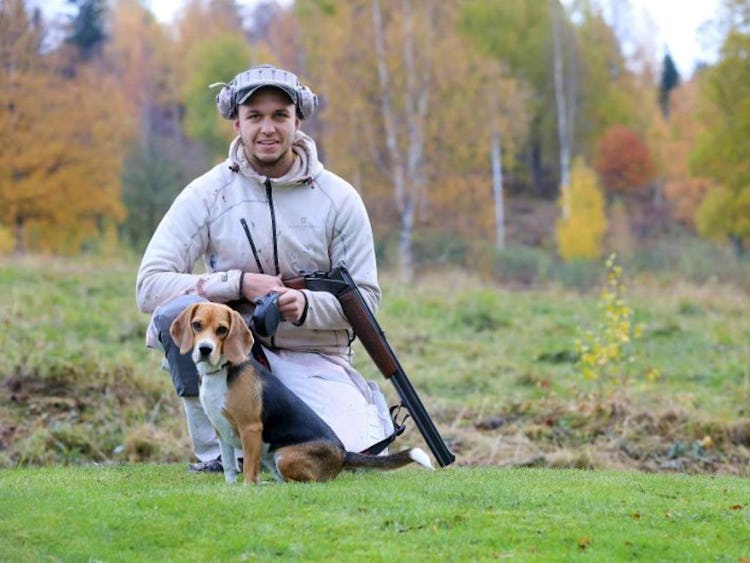 Emil Eriksson hållandes ett jaktgevär, och hans hund framför på marken