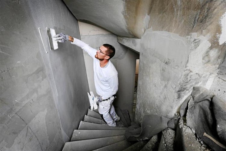 En person spacklar väggen i en trappa.