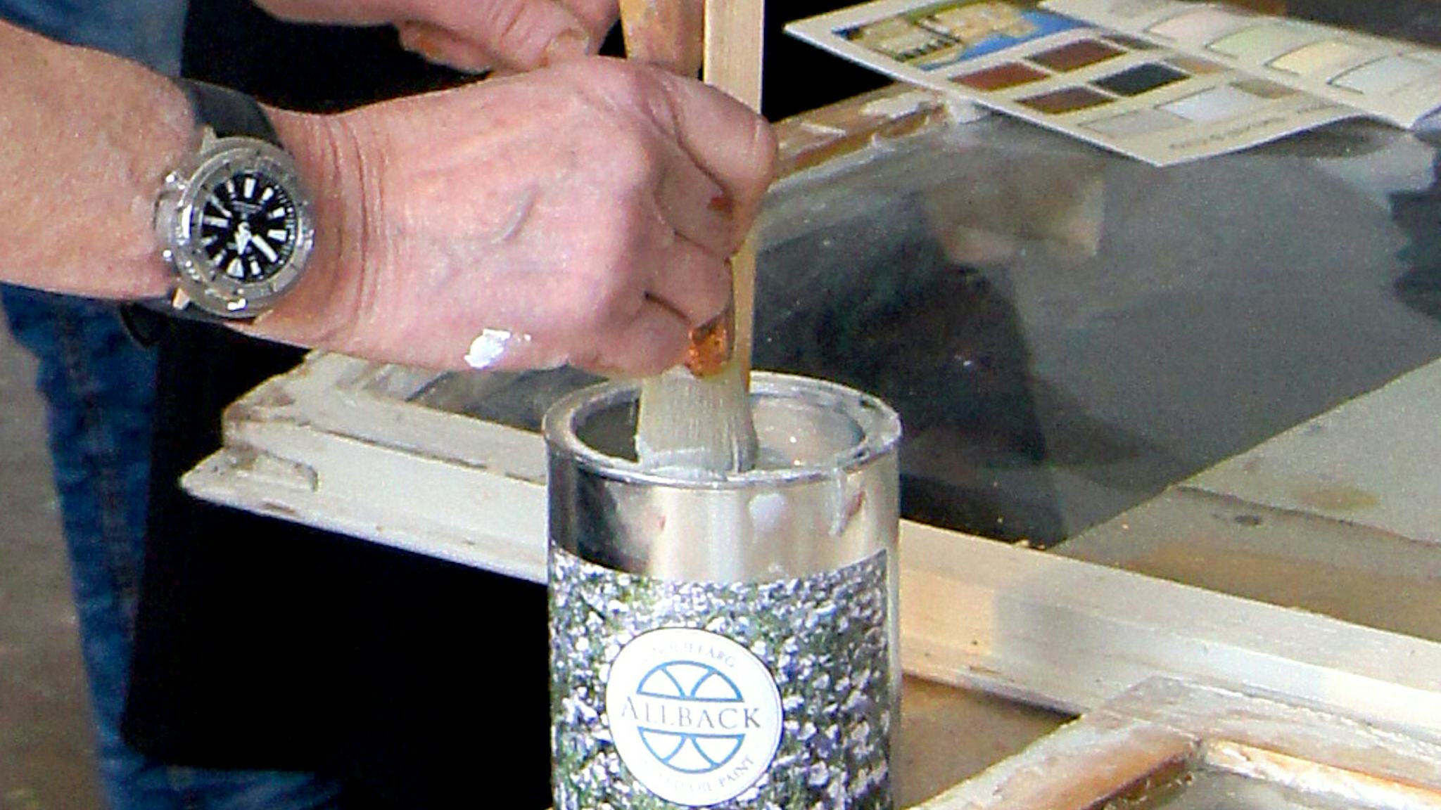 En person doppar en pensel i en burk linoljefärg