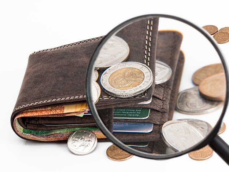 Ett förstoringsglas som zoomar in på en plånbok med pengar i