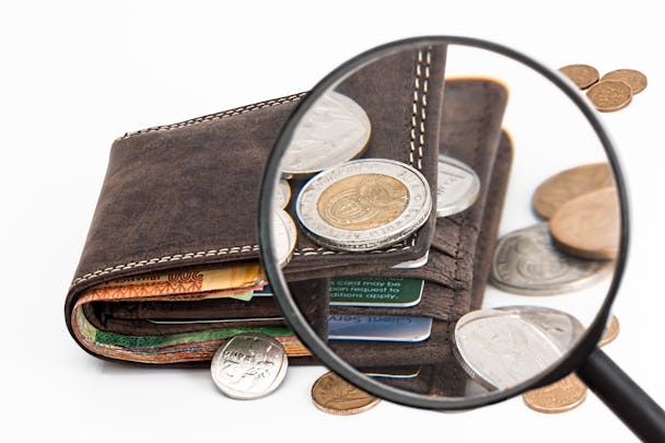 Ett förstoringsglas som zoomar in på en plånbok med pengar i