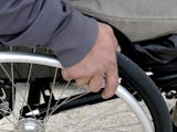 En närbild på en hand som håller i däcket på en rullstol.