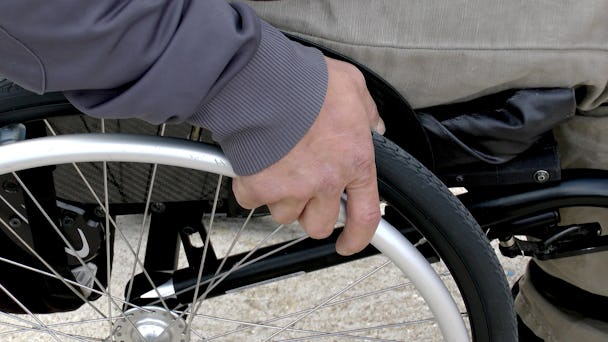 En närbild på en hand som håller i däcket på en rullstol.