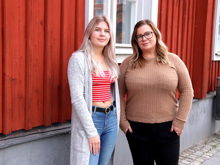 Isabelle Nilsson och Sandra Nilsson framför en röd husvägg.