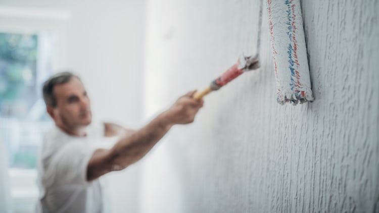 En person målar en vägg med en roller