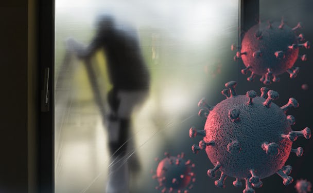 Silhuetten av en målare bakom en skyddsplast, med en bild av det nya coronaviruset monterad i hörnet