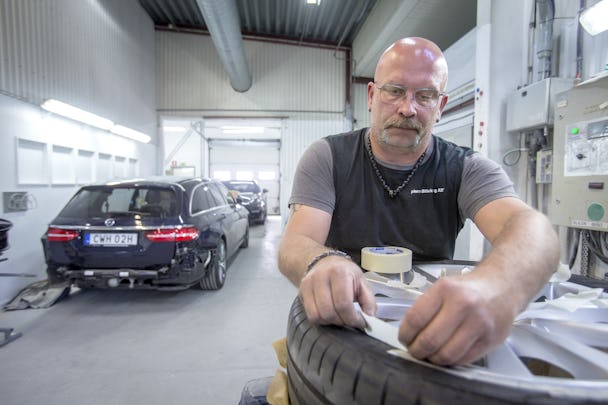 Karl-Gustav Klase arbetar vid ett bildäck i verkstaden, med en bil i bakgrunden
