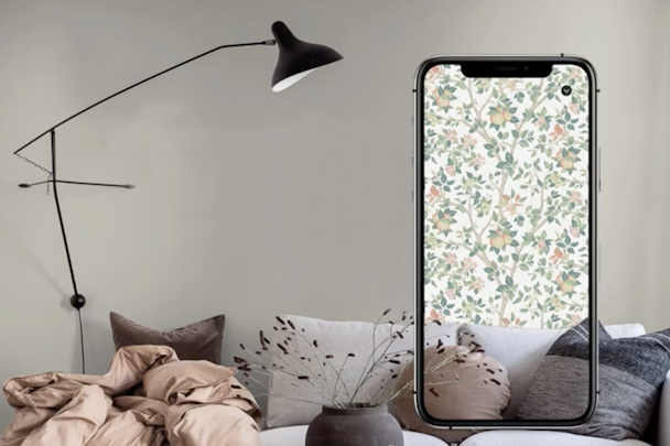 Ett vardagsrum med en överdimensionerad mobiltelefon framför, där man ser rummet med en annan tapet på väggen.