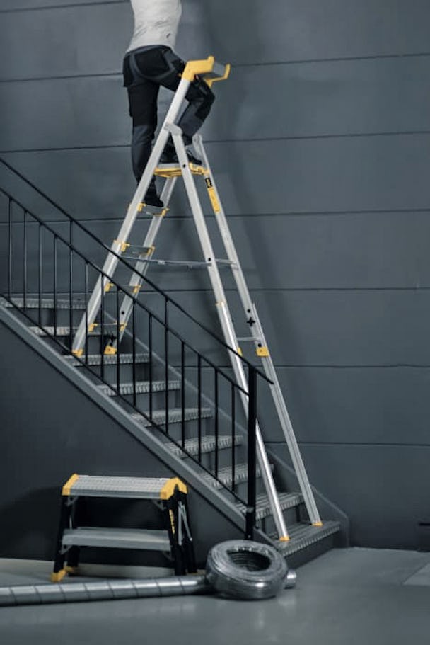 En person arbetar på en stege som står i en trappa