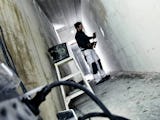 En person arbetar på en vägg i en kal korridor på ett bygge