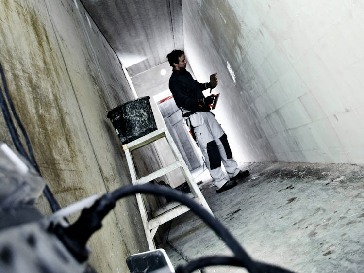 En person arbetar på en vägg i en kal korridor på ett bygge