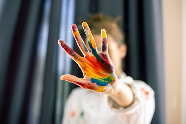 En kvinna håller upp en hand med målarfärg på i ett stopp-tecken