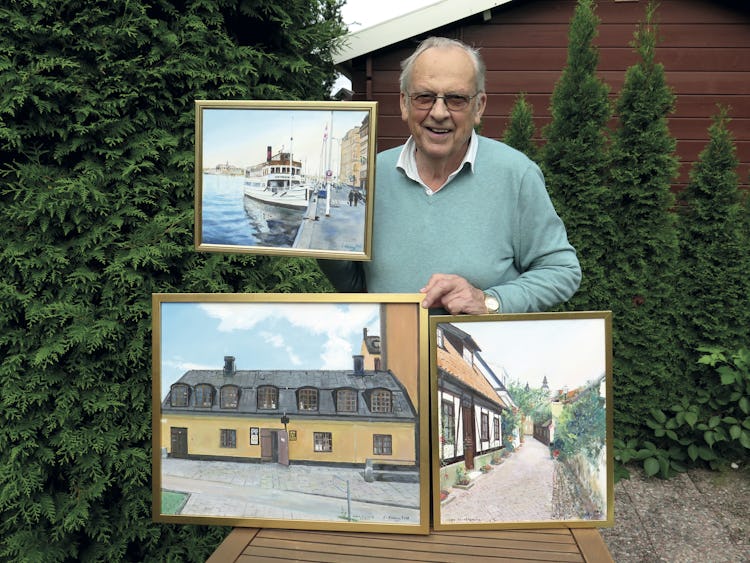 Lennart Almberg visar upp tre tavlor utomhus