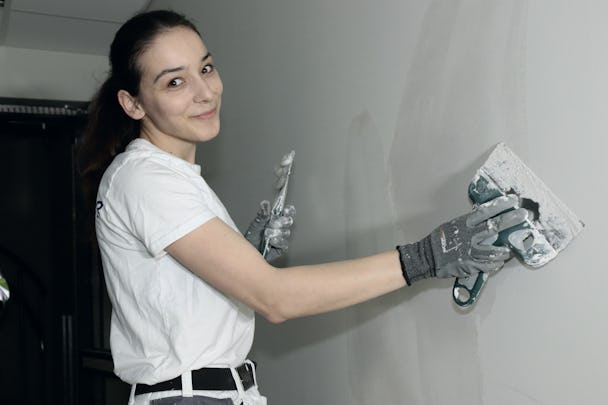 Mihaela Ciobanu jobbar med en skrapa på en vägg