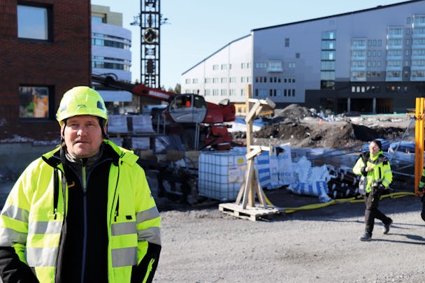 Jan-Crister Riggo dressed in helmet and yellow jacket in front of the construction site