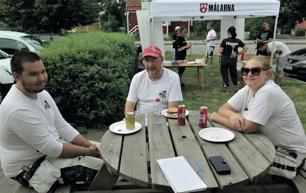 Joakim Sund, Micke Hellman och Nora Holmgren Sjöberg sitter vid ett bort utomhus