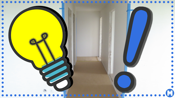 En korridor där hörnen skyddas av blå tejp, med en tecknad glödlampa och utropstecken monterade över.