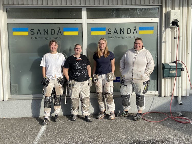 Fyra målare framför en glasruta med Sandås logga.