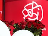 Socialdemokraternas logga bakom ett fånf röda rosor.