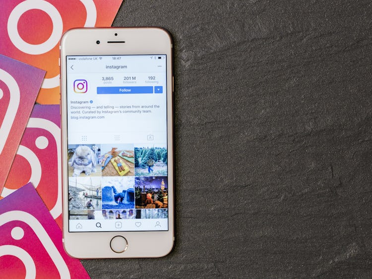 En mobiltelefon med Instagram-appen på skärmen, mot wn bakgrund av Instagram-ikoner.