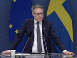 Johan Danielsson i riksdagens talarstol, framför Sveriges och EU:s flaggor