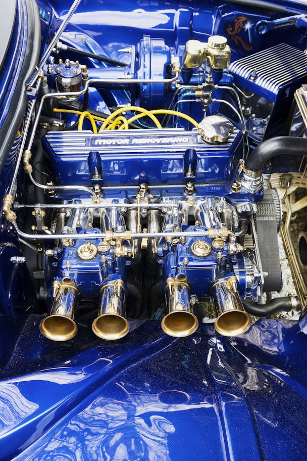 Blålackerad bilmotor med detaljer i guld och krom.