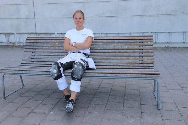 Målaren Olivia Engman sitter på en bänk utanför bandyarenan i Västerås.