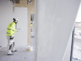 En målare rollar färg på en vägg på en byggarbetsplats