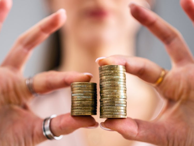 En kvinna håller i två olika höga staplar med mynt.