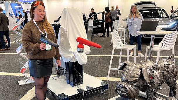 Josefine Larsson lackerar en metallhund med hjälp av en robot.