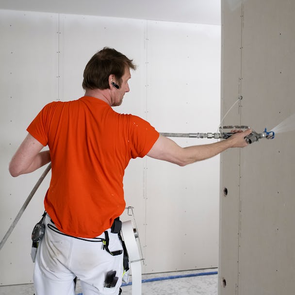 En målare som målar en vägg med en sprutpistol.