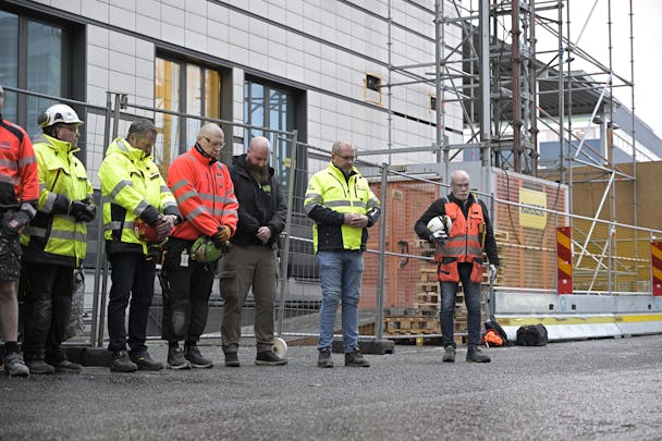 Byggnadsarbetare på en arbetsplats i Solna håller en tyst minut.